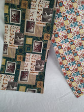 Load image into Gallery viewer, A reversible table runner with a Christmas-themed pattern featuring a variety of holiday motifs such as stars and Christmas trees, primarily in red, blue, and yellow hues, with metallic gold accents.