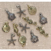 Load image into Gallery viewer, A collection of detailed metal charms with a sea life theme, including a starfish, seashell, seahorse, and sea turtle, displayed on a burlap surface.