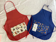 Load image into Gallery viewer, A collection of children's aprons in various designs and colors, made of cotton, displayed on a white background.

