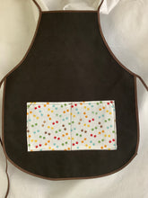 Load image into Gallery viewer, A collection of children's aprons in various designs and colors, made of cotton, displayed on a white background.
