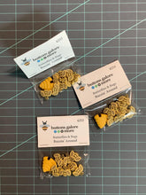 Load image into Gallery viewer, Buttons with novelty designs, labeled with 'Buzzin Around'. The buttons made of plastic and come in various shapes and colors, related to bee-related motifs.
